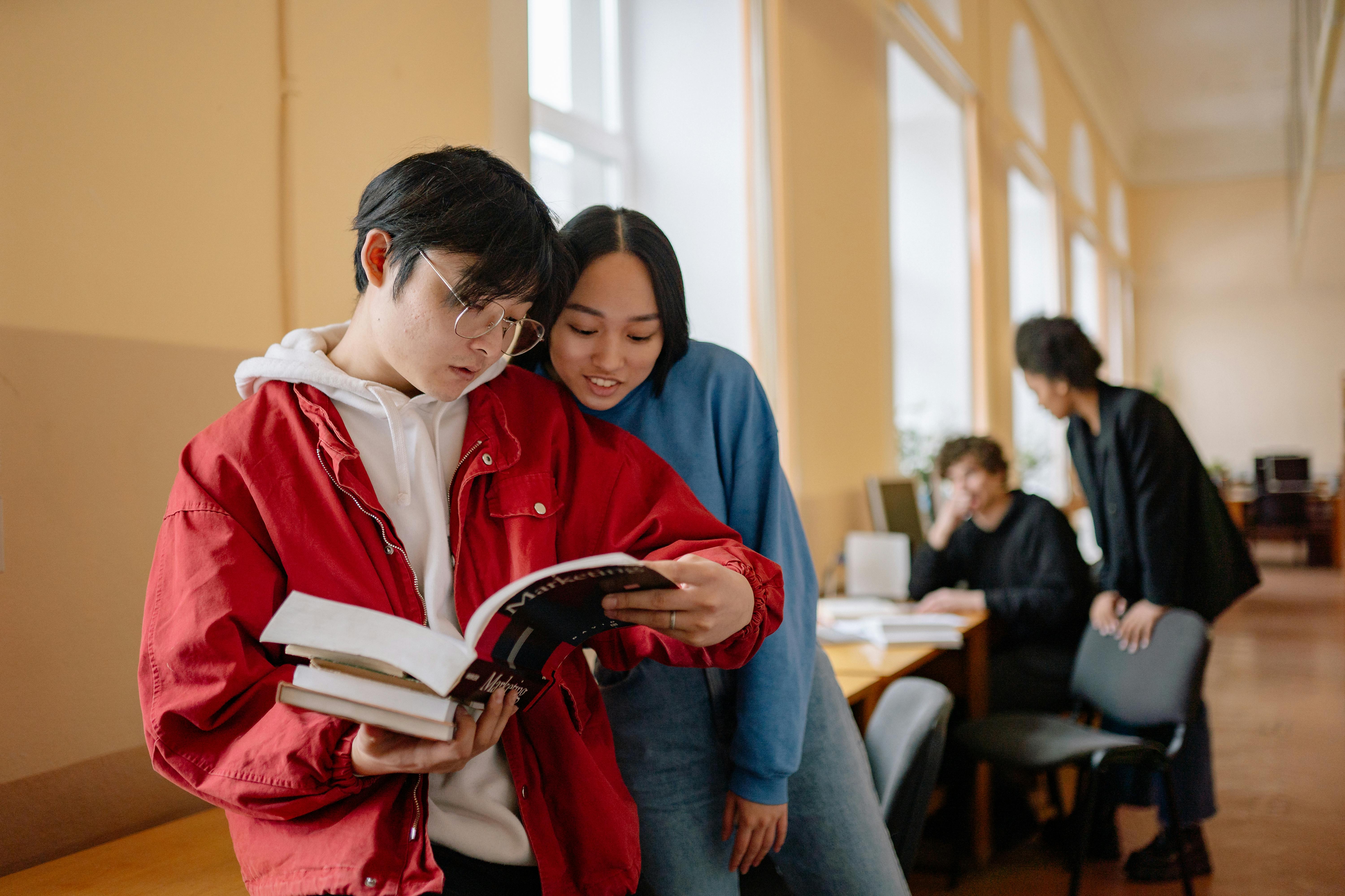 A student reading study notes by a campus bookshelf.