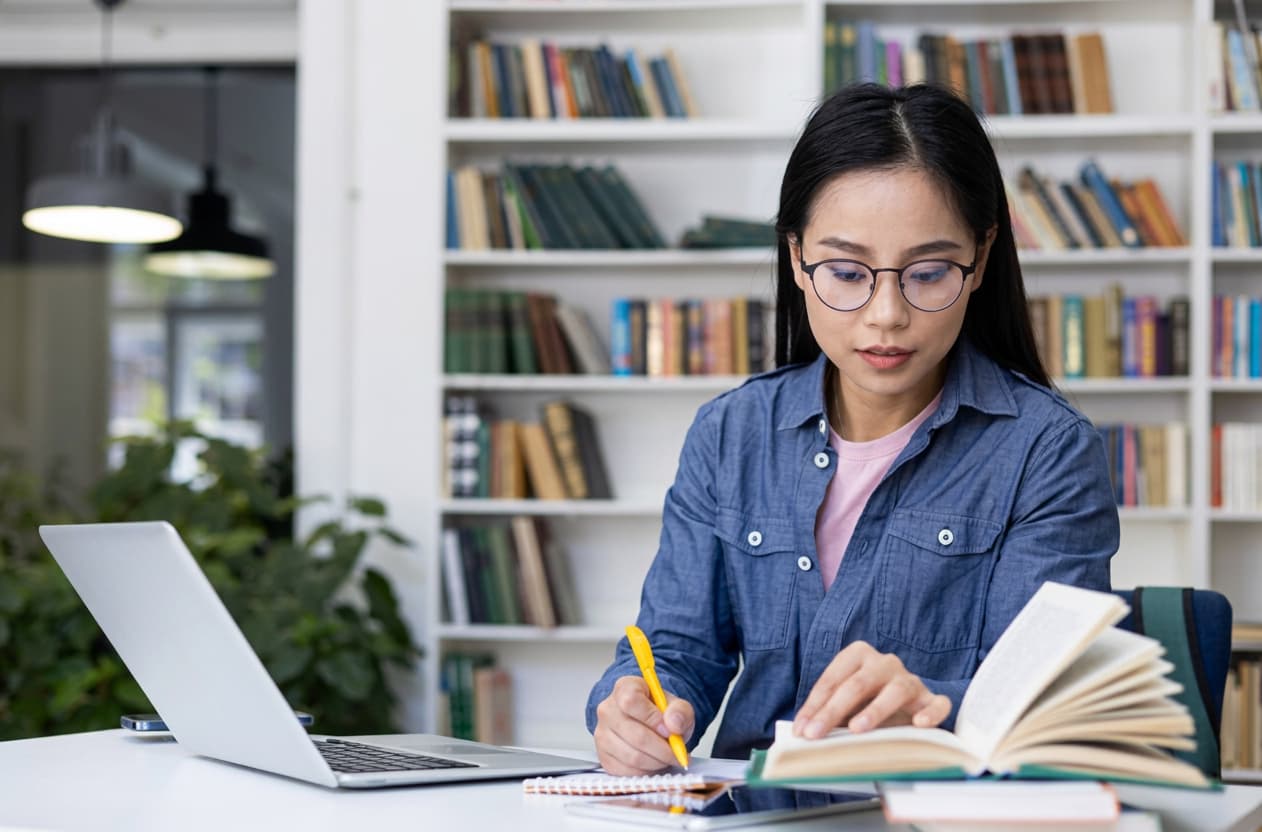A student studying on a UK campus lawn during mentorship.